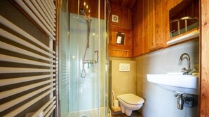 Een kleine badkamer met een douchecabine van glas, een toilet en een wastafel.