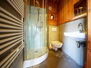 Ein kleines Badezimmer mit Duschkabine aus Glas, Toilette und Waschbecken.