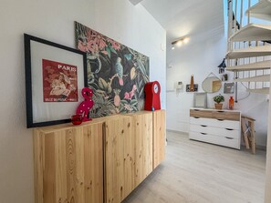 Un interior moderno con un gabinete de madera, un cartel enmarcado, un reloj rojo y una escalera.