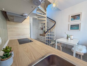 Una cocina moderna con encimera de madera, un lavamanos integrado y una escalera de caracol.