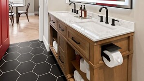 Une salle de bain avec un grand miroir, deux lavabos, un meuble-lavabo en bois et un panier de basket.