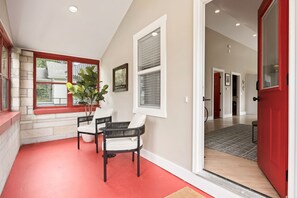 Un pasillo con una puerta roja, un banco blanco y una planta en maceta.
