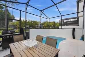 Une terrasse extérieure avec un barbecue, une piscine et un espace salon.
