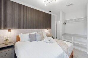 Ein modernes Schlafzimmer mit Bett, Nachttischen, einem Kleiderschrank und einem Beistelltisch.