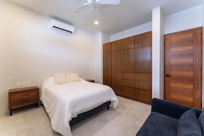 Ein Schlafzimmer mit Bett, Nachttischen, einem Kleiderschrank und einem Deckenventilator.