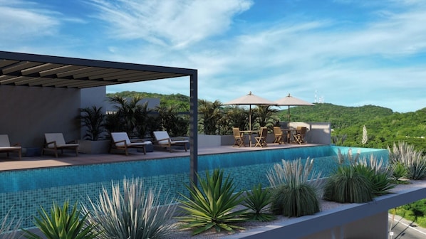 Ein Infinity-Pool auf dem Dach mit Liegestühlen und Sonnenschirmen, umgeben von tropischer Vegetation.