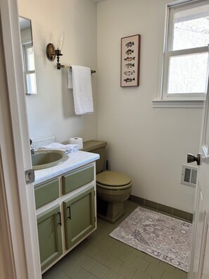 A bathroom with a sink, toilet, and a framed fish illustration on the wall. - Spacious  4-bedroom farmhouse located in East Dublin. (East Dublin)