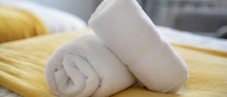 A neatly folded white towel on a yellow blanket, indicating a clean and well-maintained hotel room.