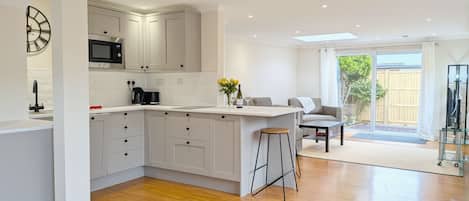 A modern kitchen with white cabinets, a central island, and a dining area with a glass table and chairs.