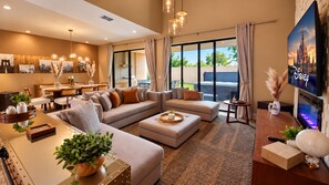 A modern living room with a sofa set, a coffee table, and a television. - Amazing home | 3 En-Suites with Jacuzzi & BBQ Near Disney (Kissimmee)