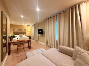 Ein Hotelzimmer mit einem Bett, einem Fernseher, einem Schreibtisch mit Stuhl und einem Sofa.