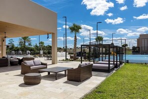 An outdoor lounge area with wicker furniture, a pool, and a covered seating area. - Amazing home | 3 En-Suites with Jacuzzi & BBQ Near Disney (Kissimmee)