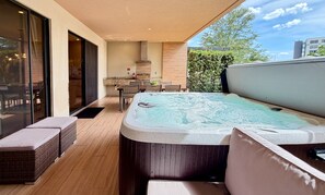 A modern outdoor hot tub area with a dining table and chairs, a large window, and a view of the sky. - Perfect Getaway | 3 En-Suites with Jacuzzi & BBQ (Kissimmee)