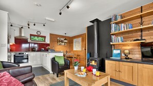 Una cucina moderna con un fornello, zona pranzo con tavolo e sedie, un divano e una libreria.