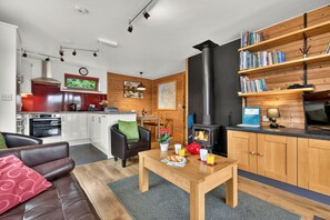 Una cocina moderna con estufa, comedor con mesa y sillas, un sofá y una estantería.