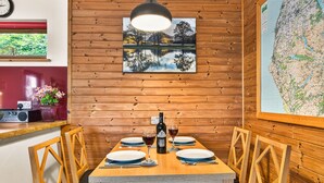 Una stanza con rivestimento in legno, un tavolo da pranzo apparecchiato per due persone, una mappa appesa al muro e una finestra con vista sul verde.
