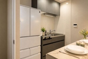 A modern kitchen with a built-in refrigerator, a stainless steel sink, and a marble countertop. - Metro House Tsuruhashi - Self Check-In (Osaka, Ikuno Ward, Tsuruhashi)