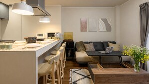 Un espai de vida modern amb una zona de cuina, un sofà, una taula de cafè i un menjador.