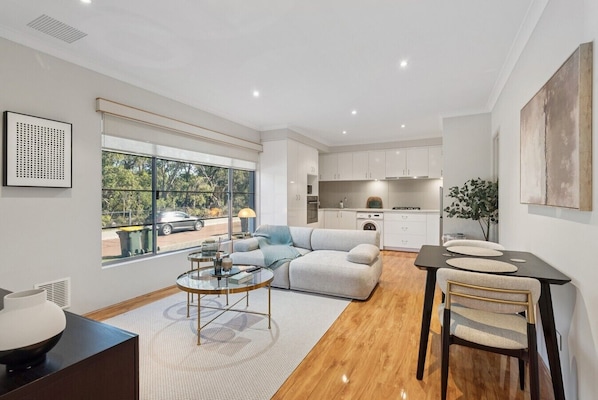 A modern apartment with a living room, dining area, kitchen, and large windows.
