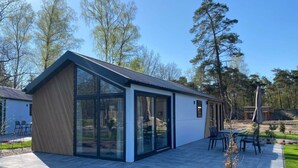 A modern house with a large glass window, a patio with outdoor furniture, and a well-maintained lawn. - Holiday Home in Arnhem With Terrace (Arnhem)