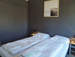Ein Hotelzimmer mit einem Bett, einem Nachttisch, einer Lampe und einem gerahmten Bild an der Wand.