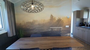 A modern kitchen with a wooden table and chairs, a pendant light, and a mural of a forest scene. - Holiday Home in Arnhem With Terrace (Arnhem)