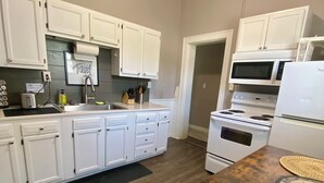 Una cocina moderna con armarios blancos, una mesa de comedor de madera y un microondas.