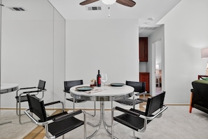 A modern dining area with a round table, black chairs, and a ceiling fan. - Charming Downtown Palm Springs Getaway 1 Bedroom Condo (Palm Springs)