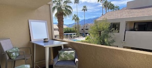 A balcony with a table and chairs, a small pool, palm trees, and a mountain view. - Charming Downtown Palm Springs Getaway 1 Bedroom Condo (Palm Springs)