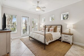 Ein Schlafzimmer mit Bett, Nachttischen, Deckenventilator und Blick durch das Fenster.
