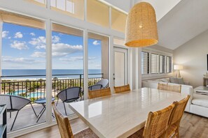 Ein geräumiger Balkon mit Meerblick, ein Essbereich mit Tisch und Stühlen sowie ein modernes Interieur mit großem Fenster und Pendelleuchte.