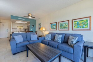 A living room with a sofa set, a coffee table, a lamp, and framed artwork on the wall. - Maui Banyan H406 1 Bedroom Condo (Kihei)