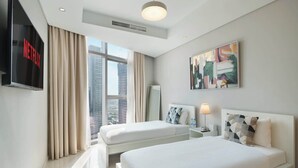 A hotel room with two beds, a TV, a painting, and a city view. - Chic 2BR in Paramount Midtown Infinity Pool Access (Dubai)