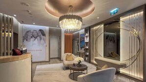 A modern hotel lobby with a reception desk, a chandelier, a round mirror, and a seating area with a round table. - Chic 2BR in Paramount Midtown Infinity Pool Access (Dubai)