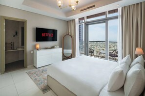 Ein Hotelzimmer mit einem großen Bett, einem Fernseher, der das Netflix-Logo zeigt, einem Balkon mit Blick und einer weißen Kommode.