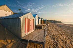 Ein Strand mit Holzstegen, die zu Strandhütten führen.