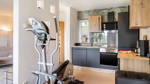 A modern kitchen with a built-in stove, a coffee machine, and wooden cabinets.