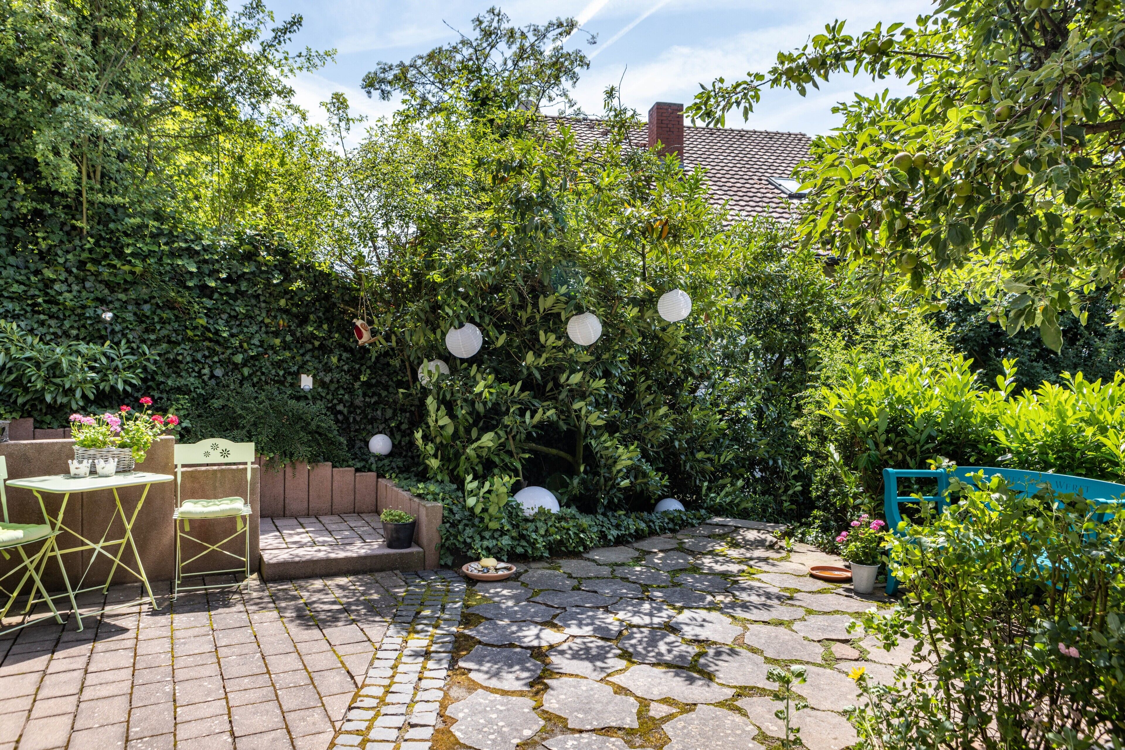 A patio with stone flooring, a wooden bench, and a table with chairs.