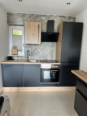 Eine moderne Küche mit Einbauofen, einem schwarzen Kühlschrank und Holzschränken.