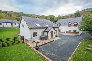 Hvide huse med grå tage, en belagt indkørsel og en græsplæne med et hegn.