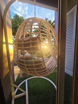 Ein Hängesessel mit weißem Gestell und Kissen, der an der Decke befestigt ist.