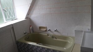 Un baño con bañera, ventana y paredes de azulejos.