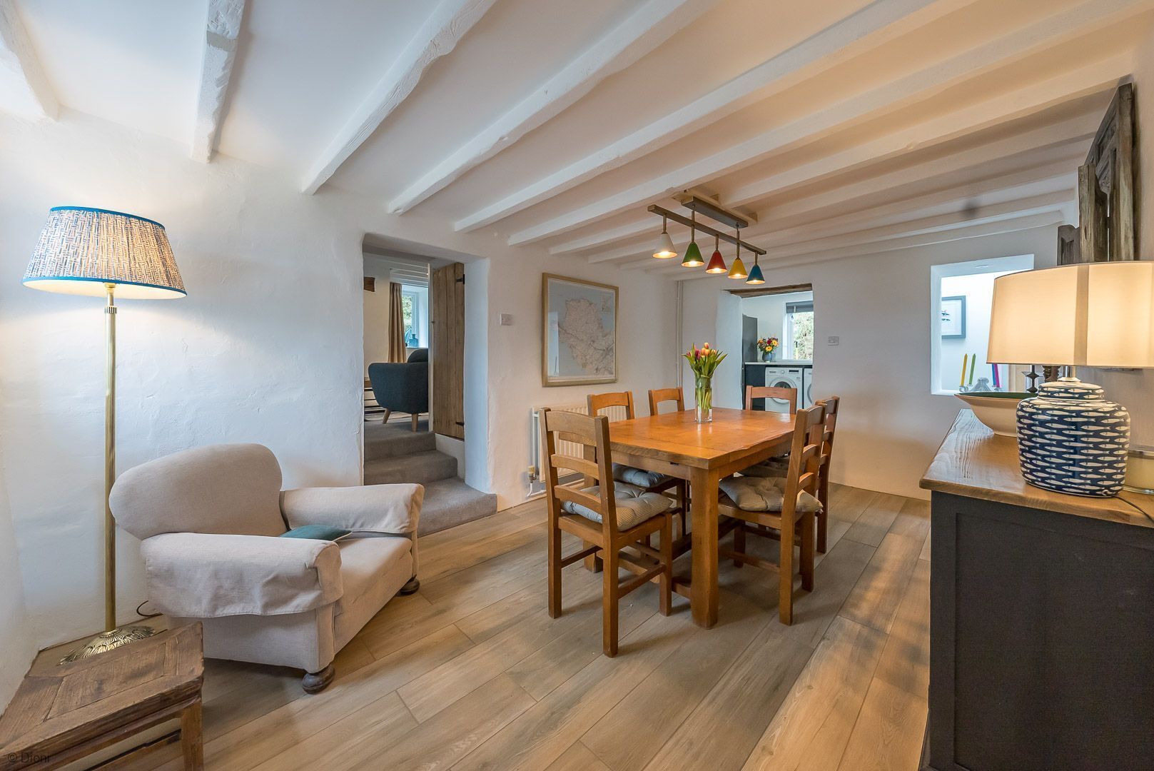 A dining area with a wooden table and chairs, a lamp, and a vase with flowers.