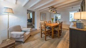 Een eetruimte met een houten tafel en stoelen, een lamp en een vaas met bloemen.