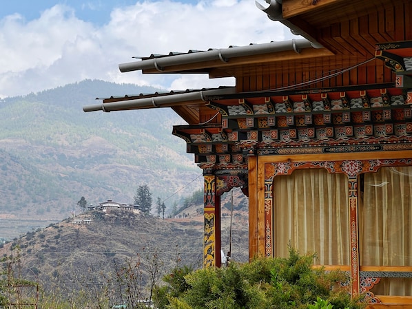 Un edificio tradicional con estructura de madera y detalles intrincados, frente a un paisaje montañoso.