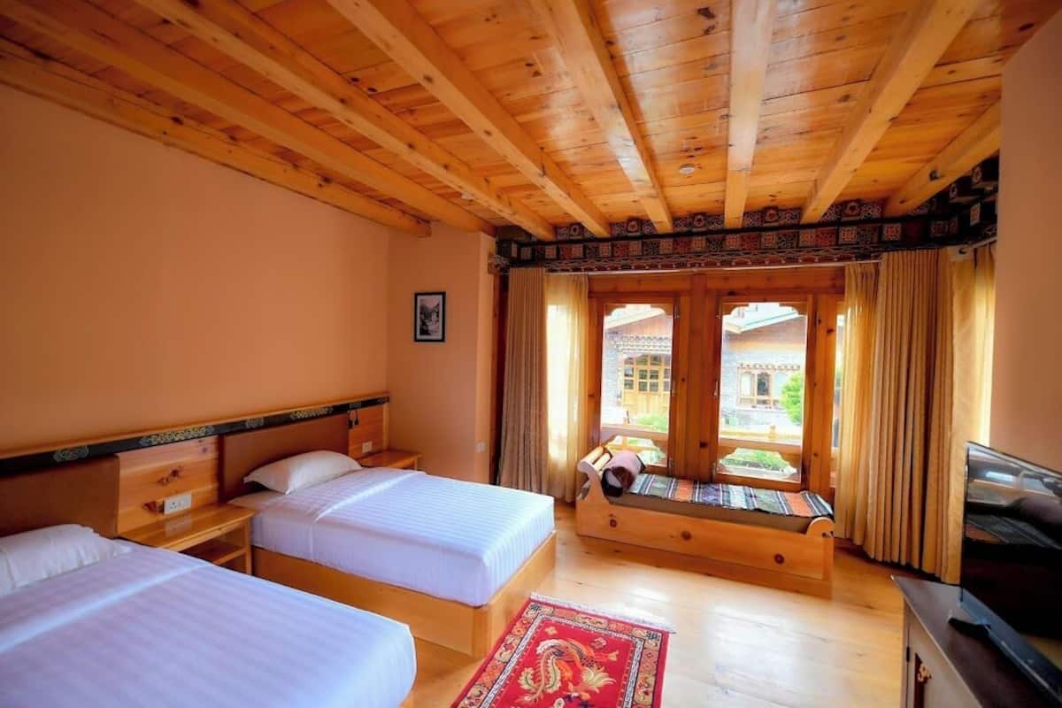 A wooden room with two beds, a TV, and a view of a building outside.