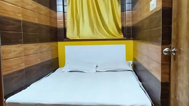 A single bed with a yellow headboard in a room with wooden panel walls.