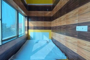 A room with a bed, a window, and wooden panel walls.
