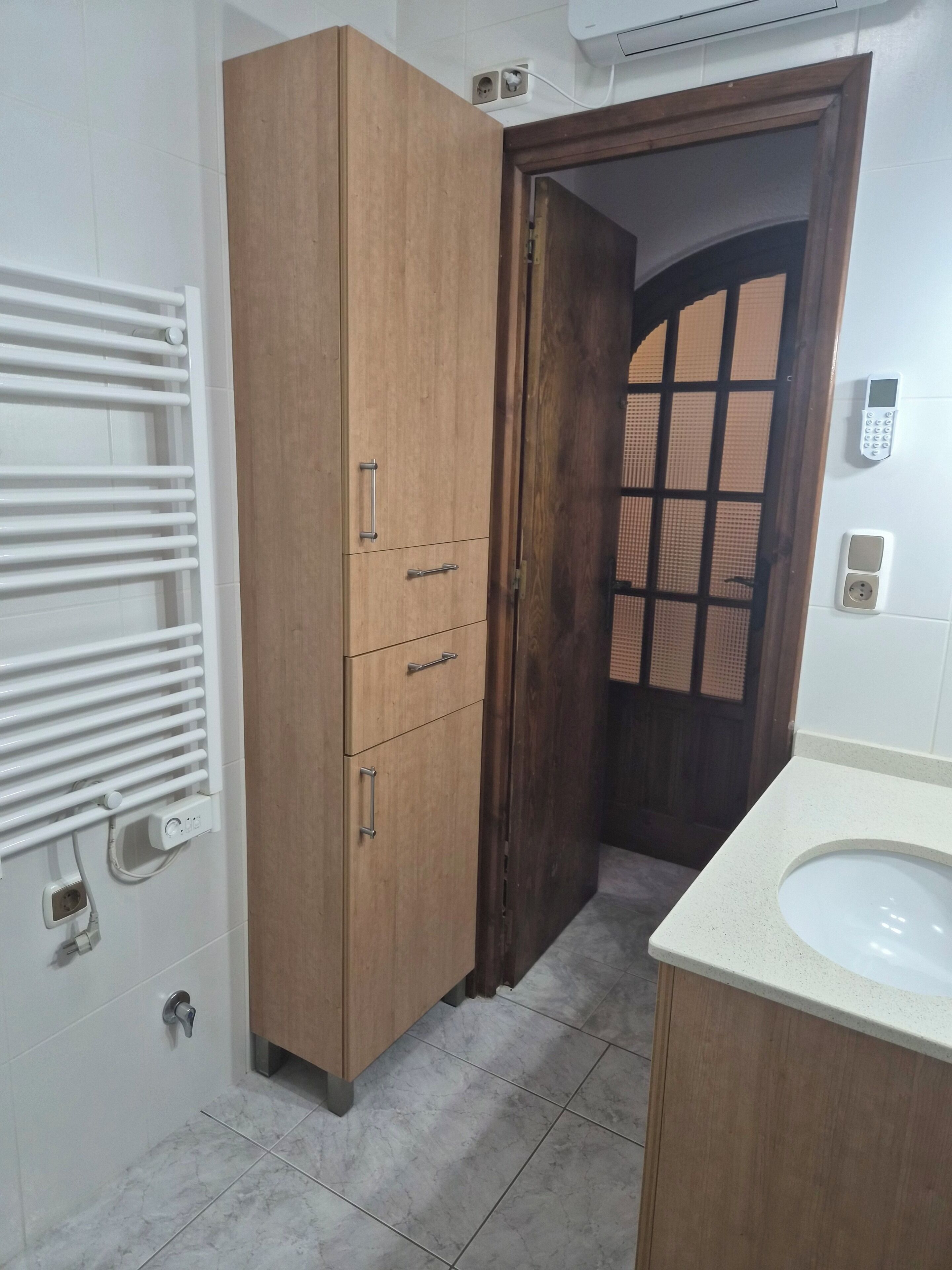 A bathroom with a wooden cabinet, a white sink, and a towel rack.