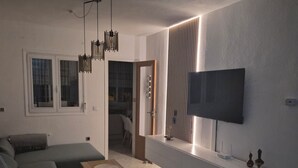 Una sala de estar moderna con un sofá, una mesa de centro, un televisor y un televisor montado en la pared.
